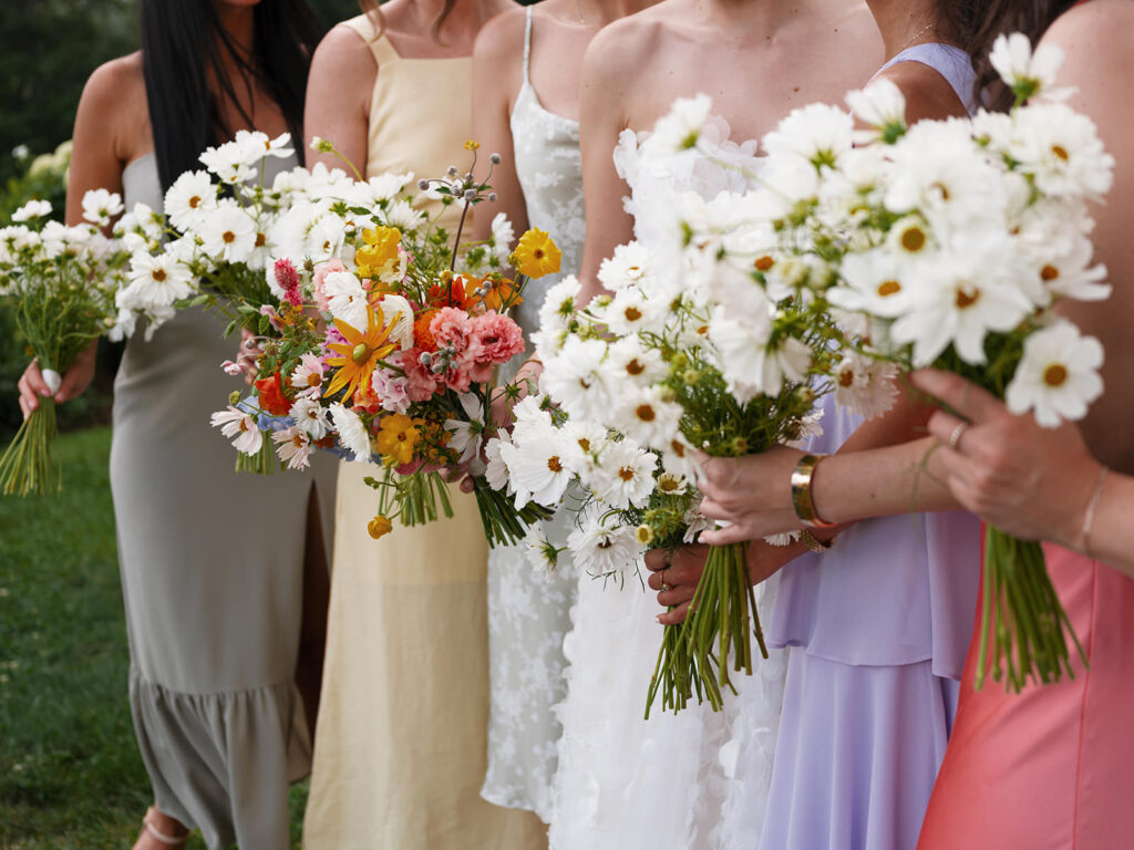 bridesmaids holding all white bouquets wearing colorful dresses