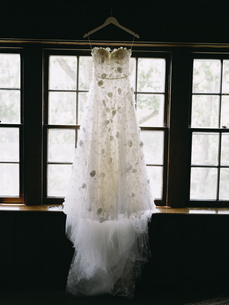 Bride's dress hanging in front of a window